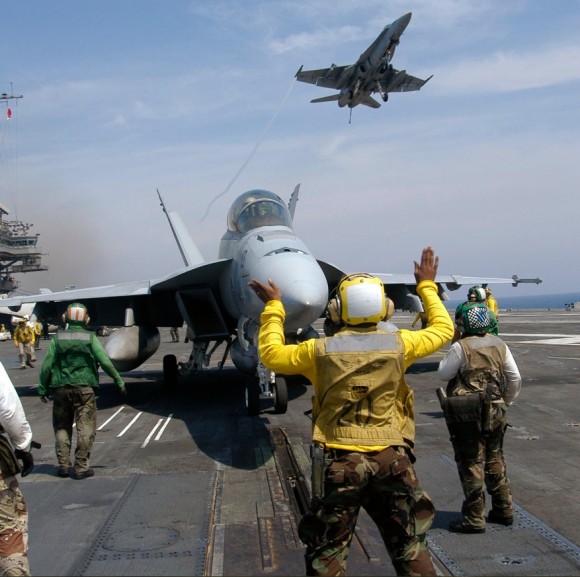 Hornet sobrevoa CVN 63 enquanto Super Hornet é preparado para lançamento - foto Marinha dos EUA