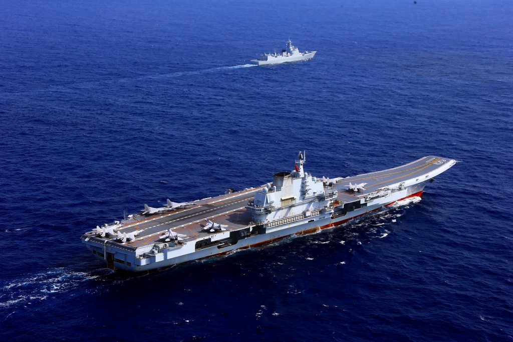 O porta-aviões Liaoning e ao fundo um destróier Type 052